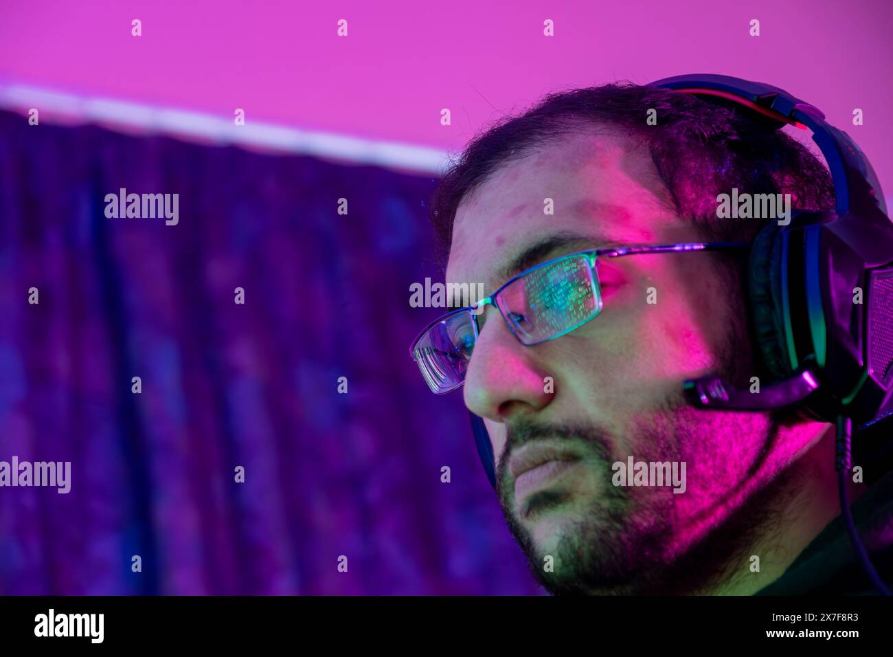 Jeune homme confiant jouant au jeu vidéo informatique en ligne, diffusion d'éclairage coloré en streaming en direct à la maison. Gamer lifestyle, E-Sport jeu en ligne tec Banque D'Images