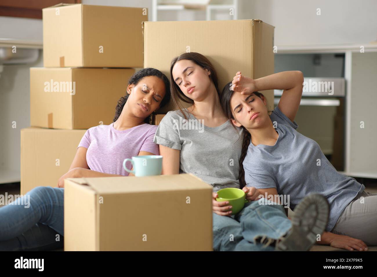 Trois femmes multi-ethniques fatiguées déménageant assis sur le sol Banque D'Images