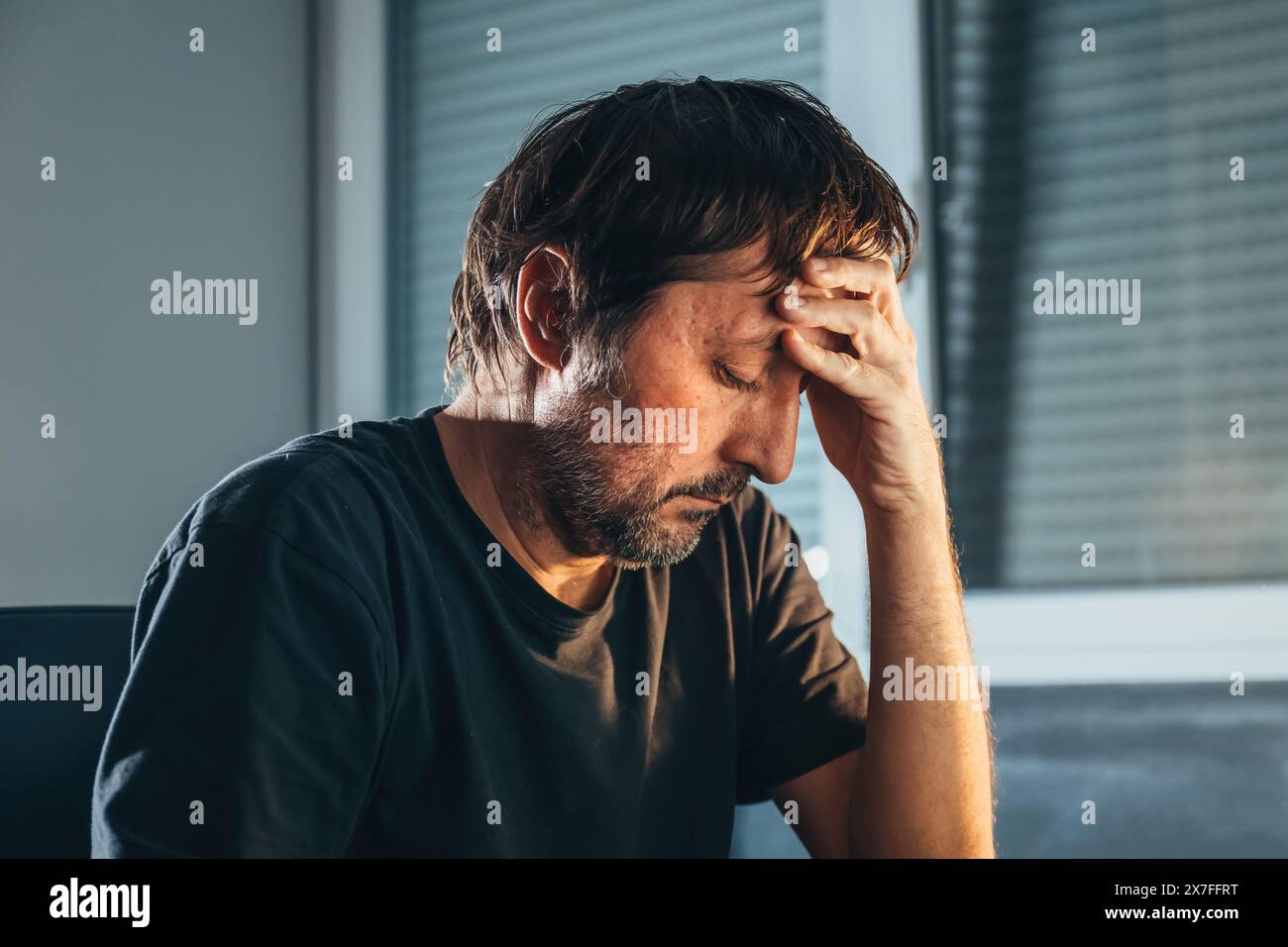 Homme adulte solitaire et déprimé avec les yeux fermés à la maison. Homme non rasé triste et malheureux. Concept de santé mentale et de regret. Mise au point sélective. Banque D'Images