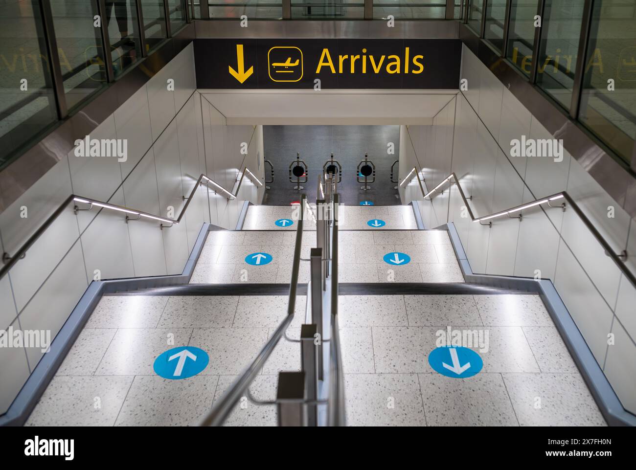 Un escalier avec des flèches bleues menant aux arrivées au terminal nord de l'aéroport de Londres Gatwick, Royaume-Uni. Banque D'Images