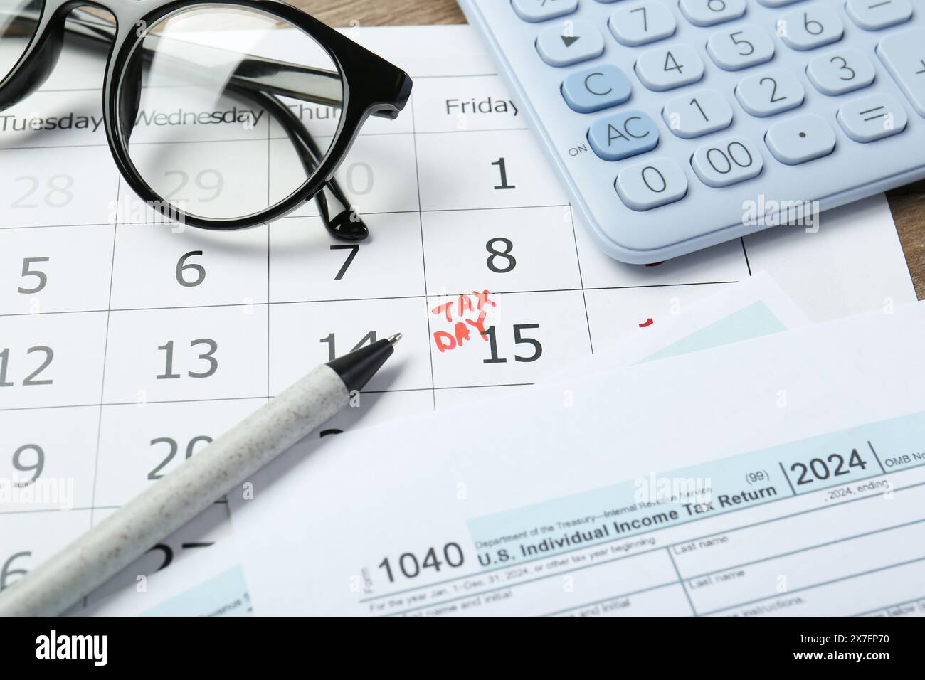 Calendrier avec rappel de date sur le jour des impôts, documents, stylo, lunettes et calculatrice sur la table, gros plan Banque D'Images