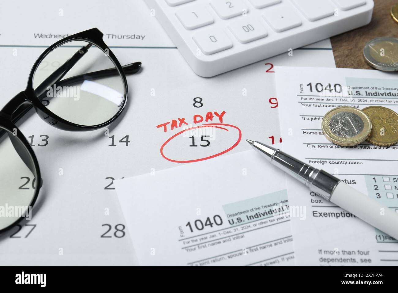 Calendrier avec rappel de date sur le jour de l'impôt, documents, stylo, pièces de monnaie, lunettes et calculatrice sur la table, gros plan Banque D'Images