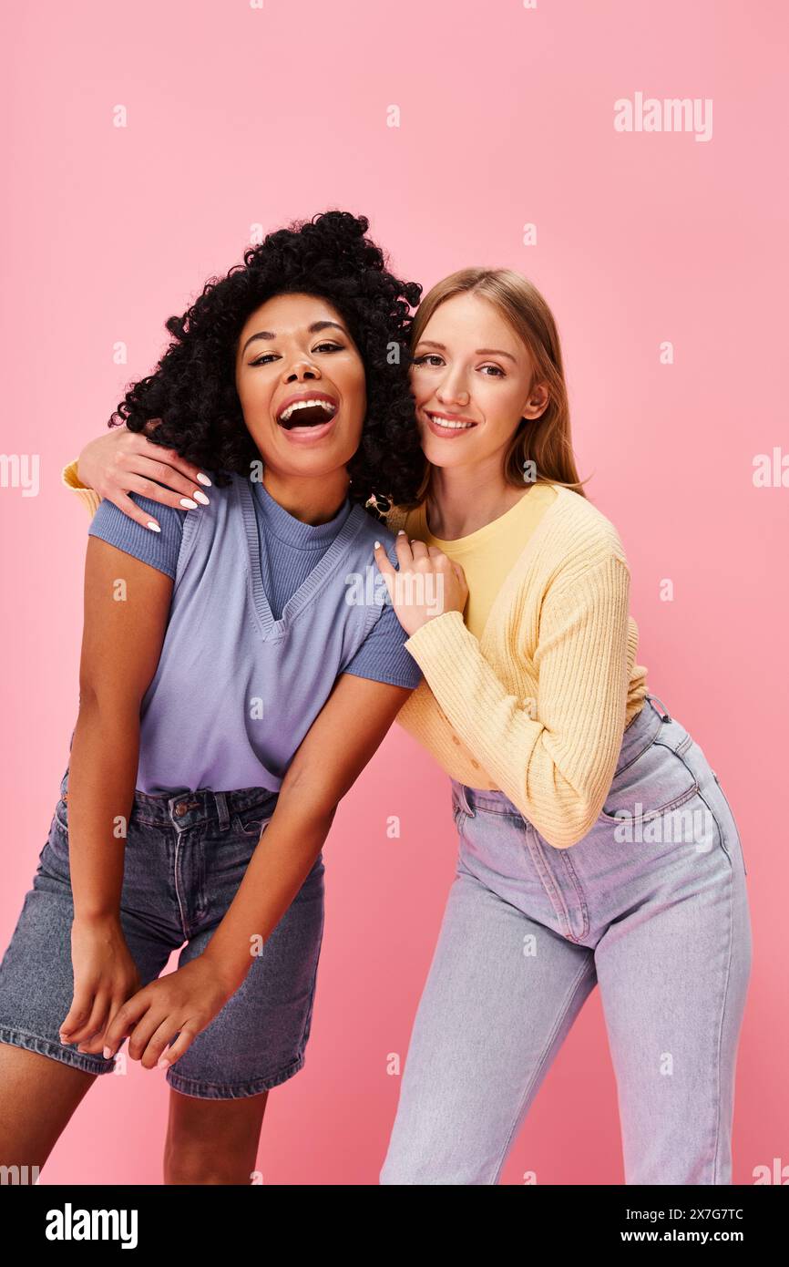 Deux femmes diverses debout en toute confiance dans une tenue décontractée confortable sur un fond rose. Banque D'Images