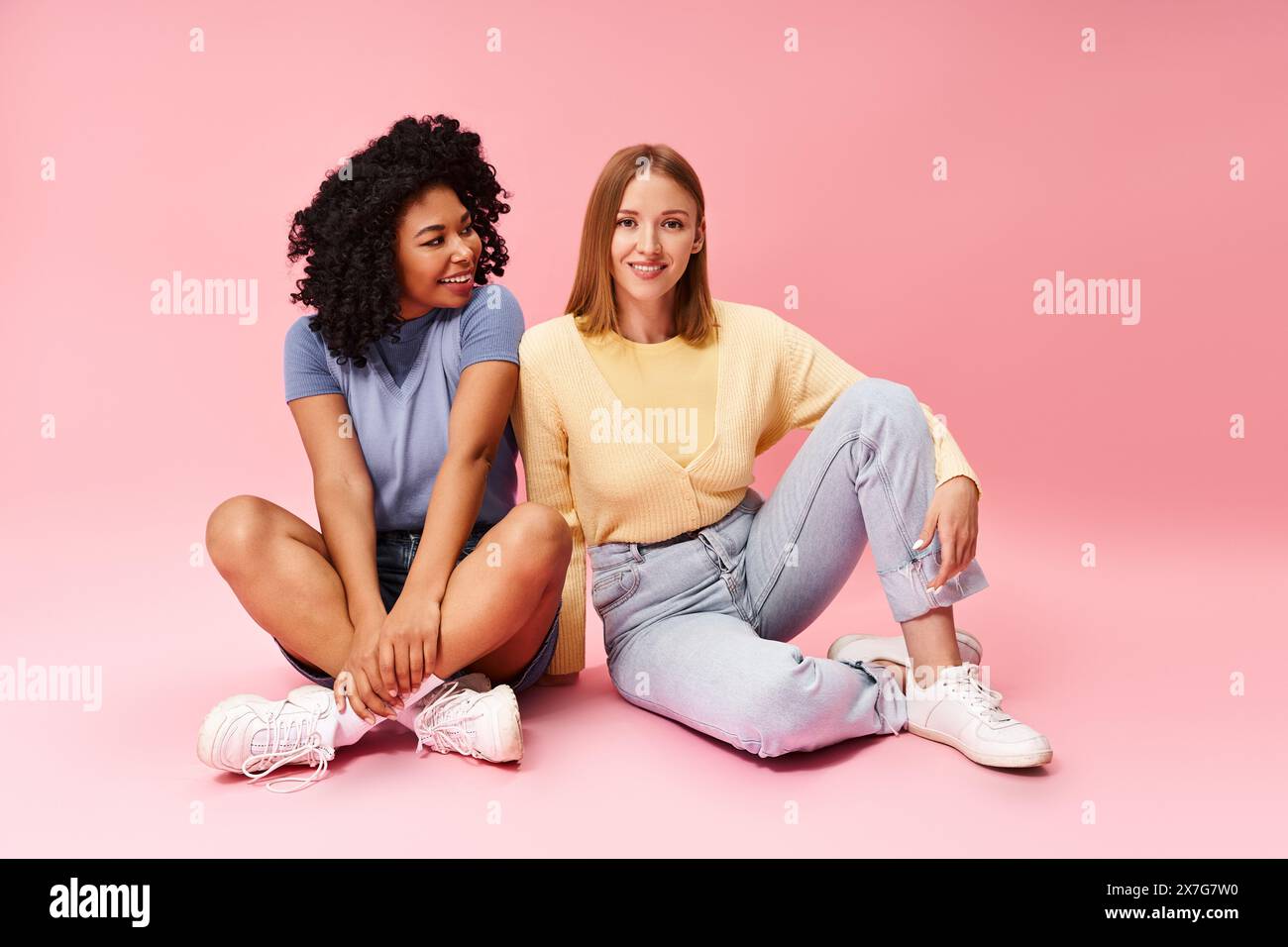 Deux femmes diverses assises sur le sol, les jambes croisées. Banque D'Images