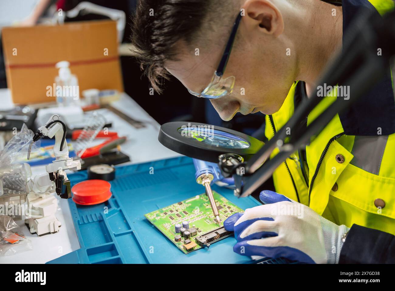 Technicien électricien utilisant un fer à souder chaud pour réparer la petite carte de circuit imprimé électrique numérique réparer avec de l'étain de soudure et du plomb Banque D'Images