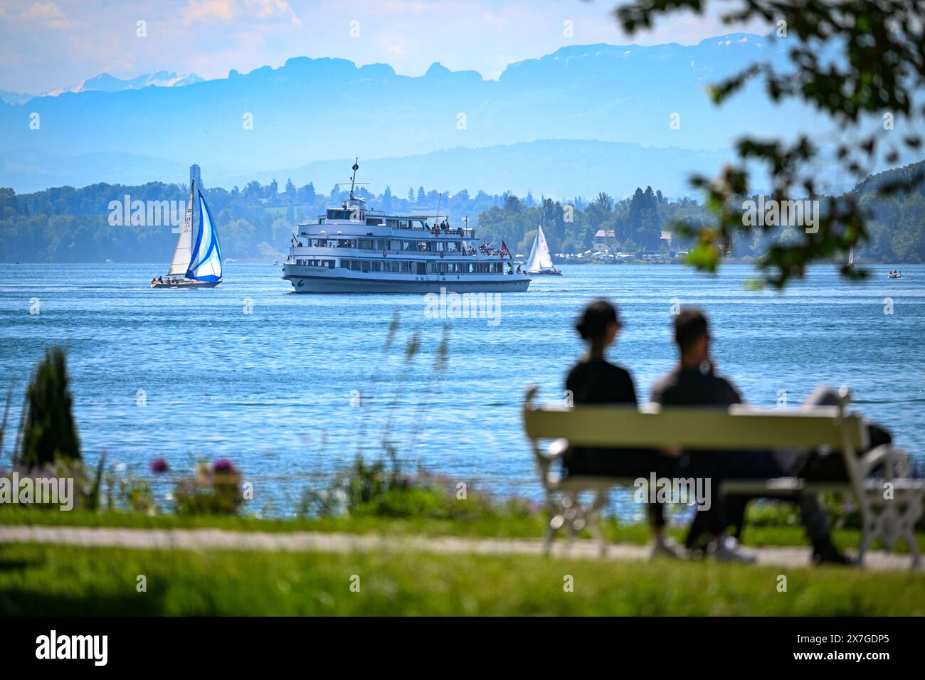 20 mai 2024, Bade-Württemberg, Überlingen am Bodensee : le navire à passagers Stuttgart navigue sur le lac de Constance jusqu'à l'embarcadère, tandis qu'au premier plan un couple est assis sur un banc dans le parc riverain. Photo : Felix Kästle/dpa Banque D'Images