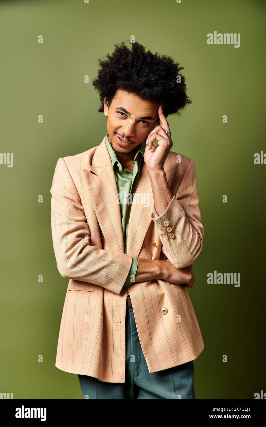 Jeune homme afro-américain en costume bronzé, chemise verte sur fond vert. Banque D'Images