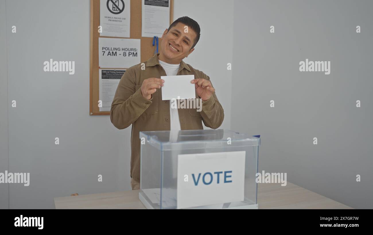 Un homme hispanique souriant qui a voté dans une cabine de vote pendant une élection. Banque D'Images