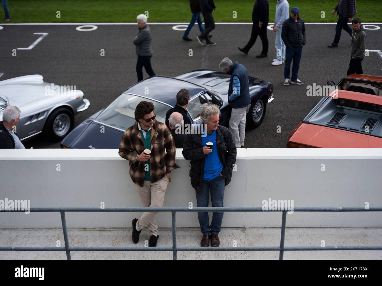 Deux hommes prenant un café sur le mur de la fosse au 100ème Breakfast Club sur le circuit de course automobile de Goodwood, Chichester, West Sussex, Royaume-Uni Banque D'Images