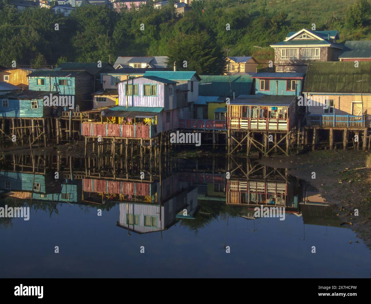 Palafitos colorés ou maisons de pêcheurs sur pilotis reflétés dans une crique au lever du soleil à Castro sur l'île de Chiloe, Chili. Banque D'Images