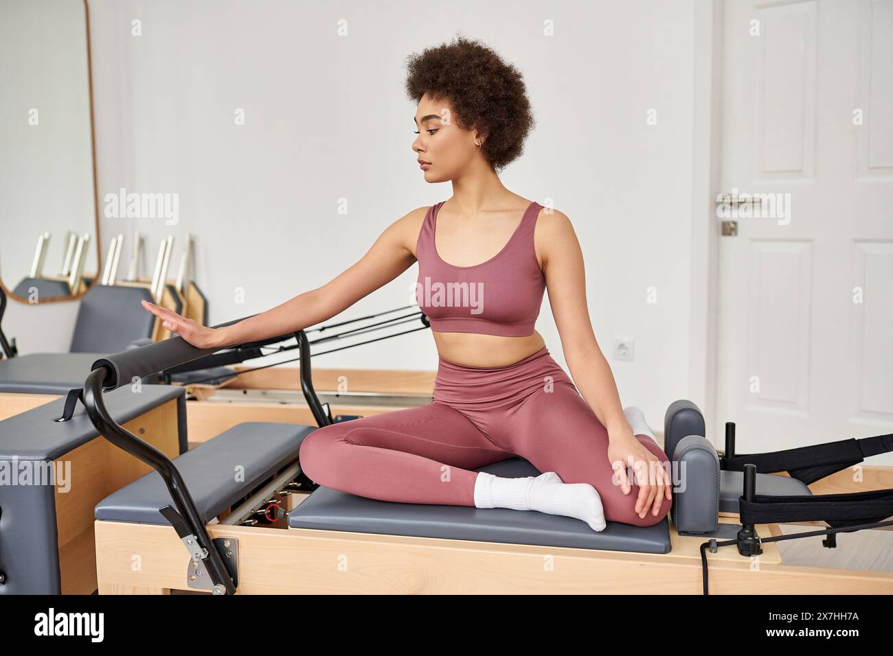 Femme pratiquant pilates assise sur un tapis dans un cadre de classe paisible. Banque D'Images
