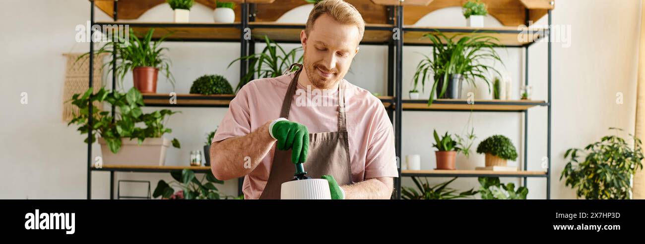 Un homme avec une chemise rose tient habilement un pinceau vert dans une petite usine, incarnant l'art de la floraison. Banque D'Images