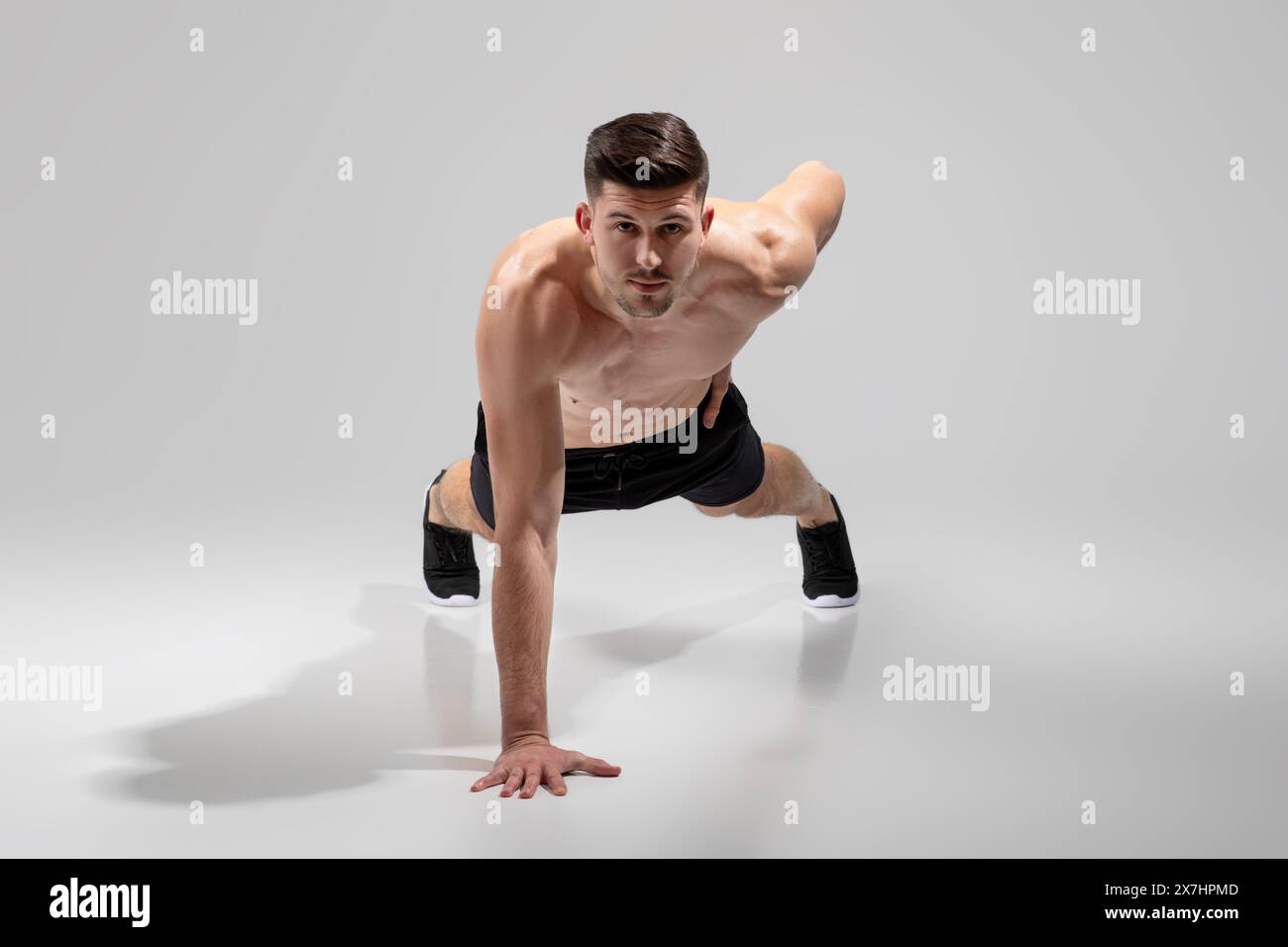 Fit Young Man Performing Plank exercice dans Minimalist Studio Banque D'Images