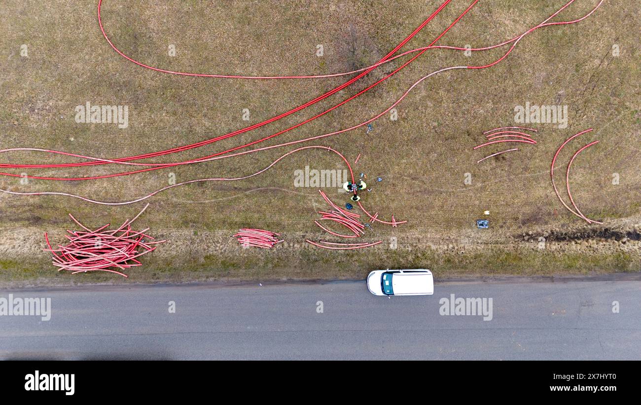 Photographie par drone de travailleurs de la construction, machines industrielles posant un nouveau pipeline près d'une route pendant la journée nuageuse du printemps Banque D'Images