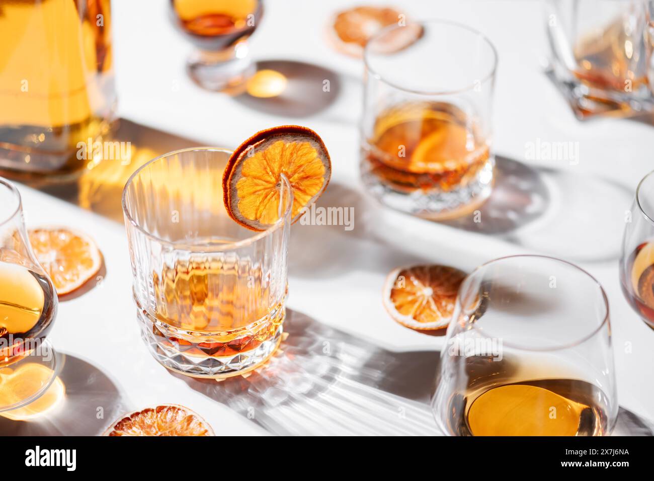 Verres de forme différente avec whisky sur table blanche. Décoration d'oranges séchées. Concept d'alcool Banque D'Images