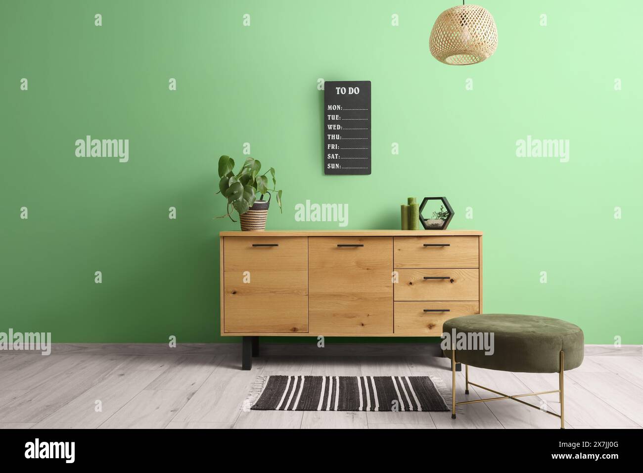 Commode en bois avec décor et pouf près du mur vert dans l'intérieur élégant du salon Banque D'Images