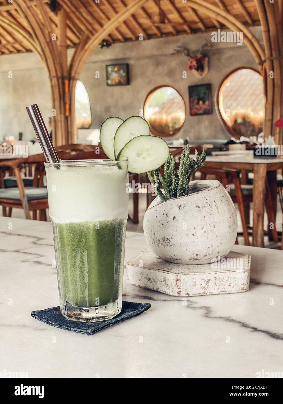Smoothie vert au concombre dans un verre avec une paille en métal sur une table en marbre en gros plan Banque D'Images