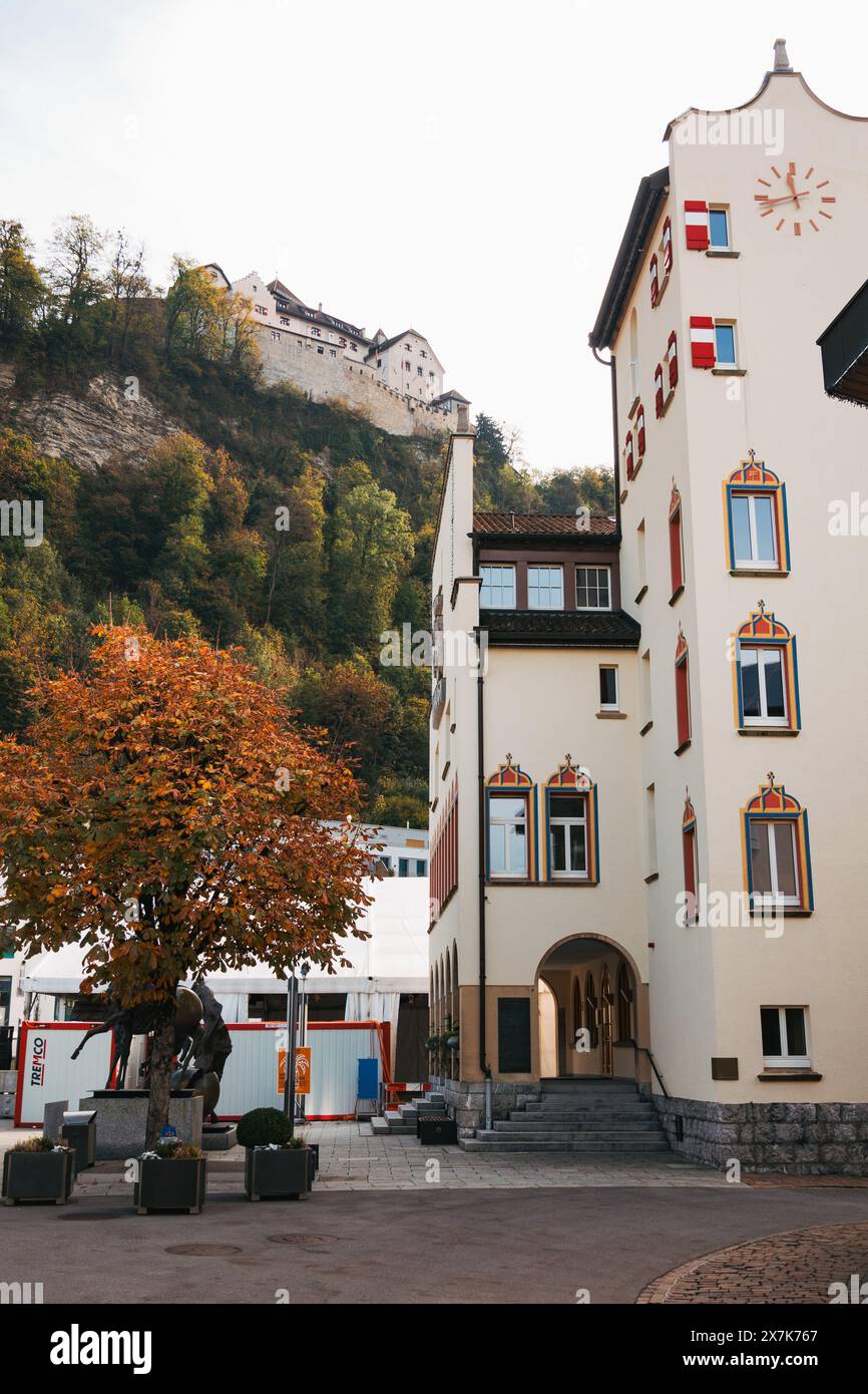 Un bâtiment blanc avec tour de l'horloge dans le centre-ville de Vaduz, Liechtenstein, avec le château en arrière-plan Banque D'Images