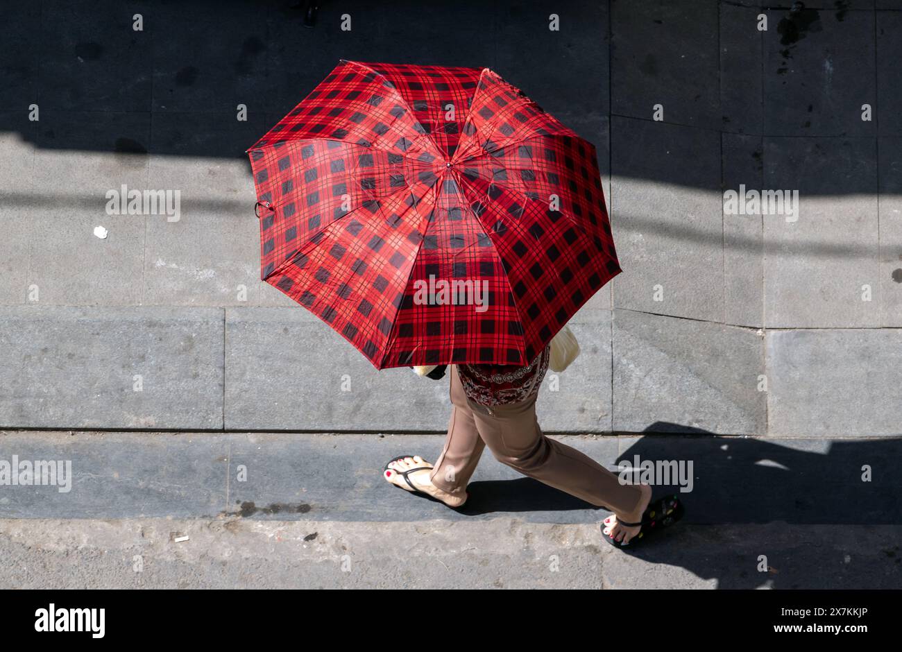 Un marcheur dans la rue de la ville se cache sous un parasol, Ho Chi Minh ville. Banque D'Images