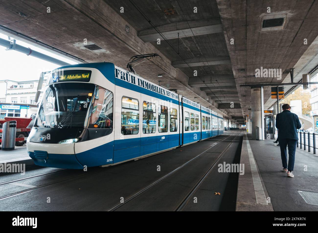 Un tramway arrive à la station de métro léger de Schiffbau, Zurich, sous une route à plusieurs voies surélevée par des piliers en béton Banque D'Images