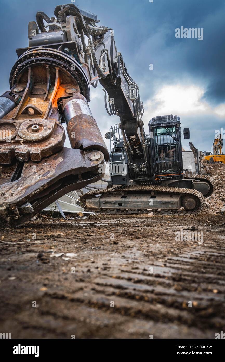 Une excavatrice est active sur un chantier, entouré de gravats et sous un ciel sombre et nuageux, démolition, Saarbruecken, Allemagne Banque D'Images