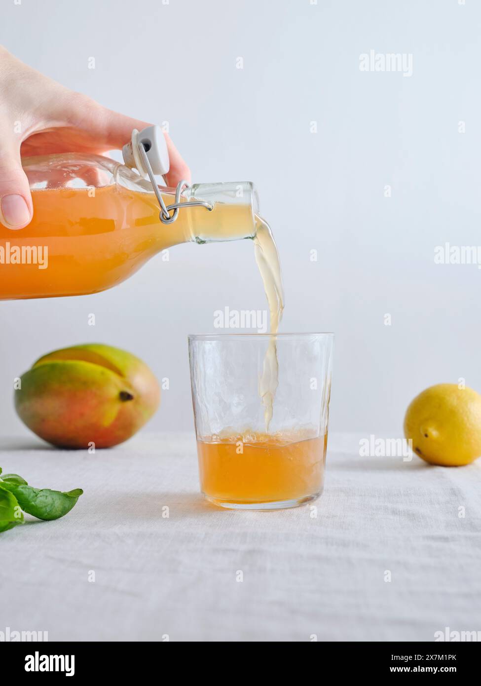 Main femelle versant de la limonade kombucha fermentée maison bio d'une bouteille dans un verre Banque D'Images