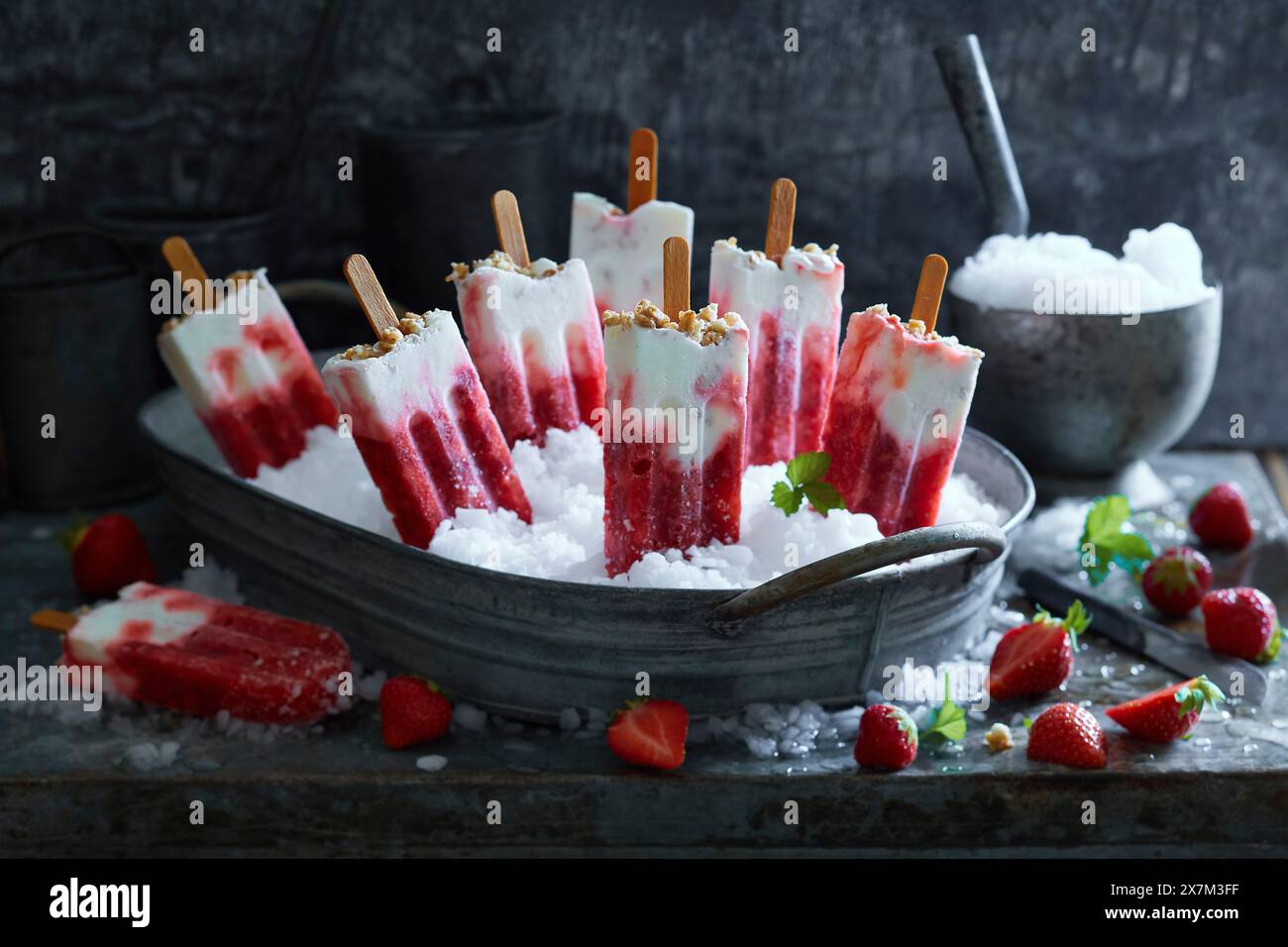 Popsicles au yogourt à la fraise faites maison sur de la glace pilée dans un bol en métal sur un fond en métal gris Banque D'Images