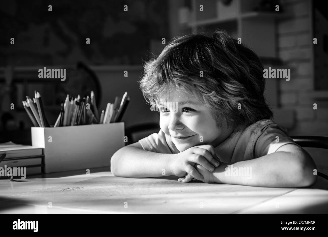 Joli visage de la pupille, gros plan.L'élève apprend des lettres et des chiffres.Apprentissage des enfants.Un enfant mignon dans la salle de classe près du bureau du tableau noir. Banque D'Images