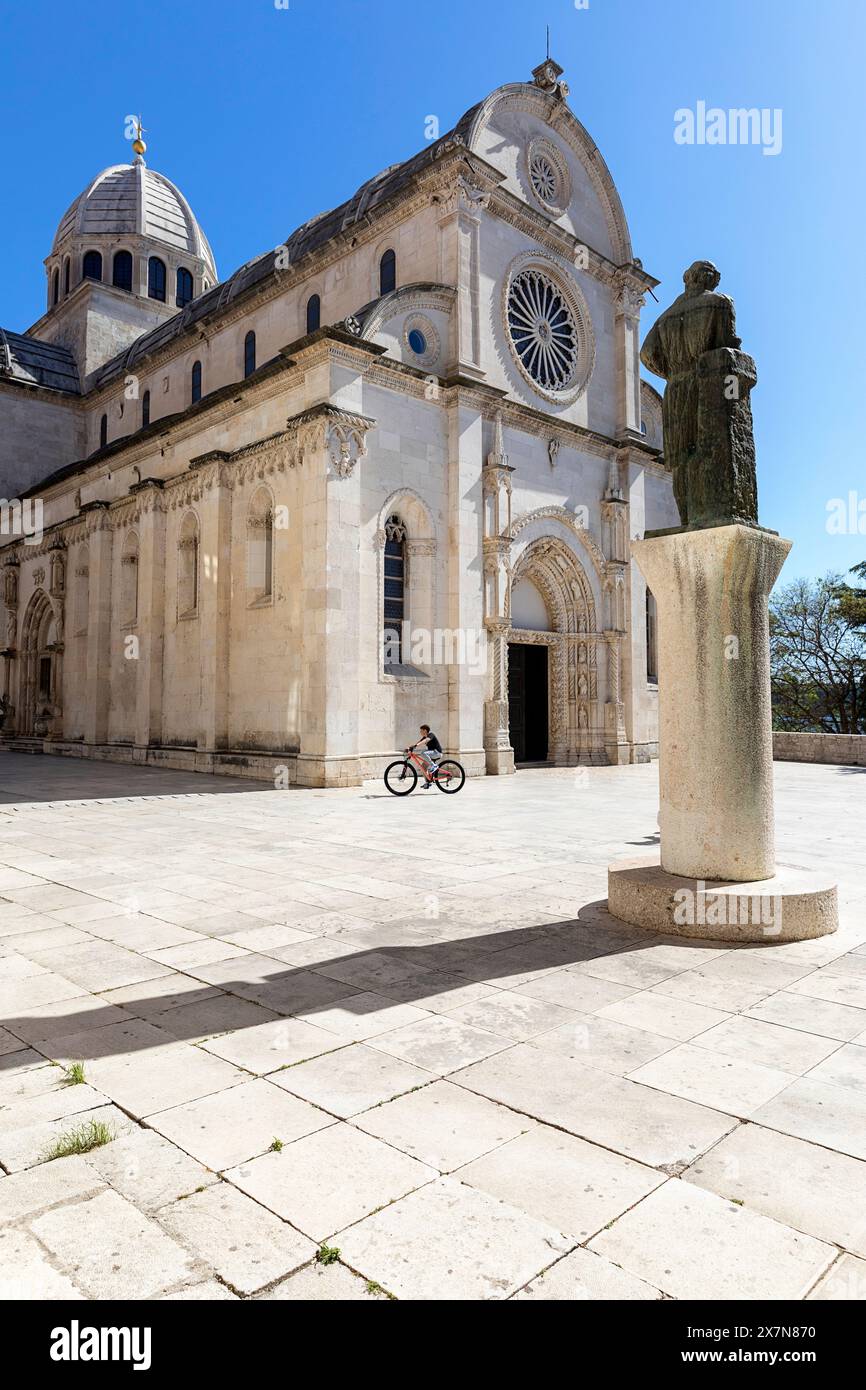 Enfant local sur un vélo devant une belle cathédrale de St James à Sibenik, en belle pierre de marbre, Croatie Banque D'Images