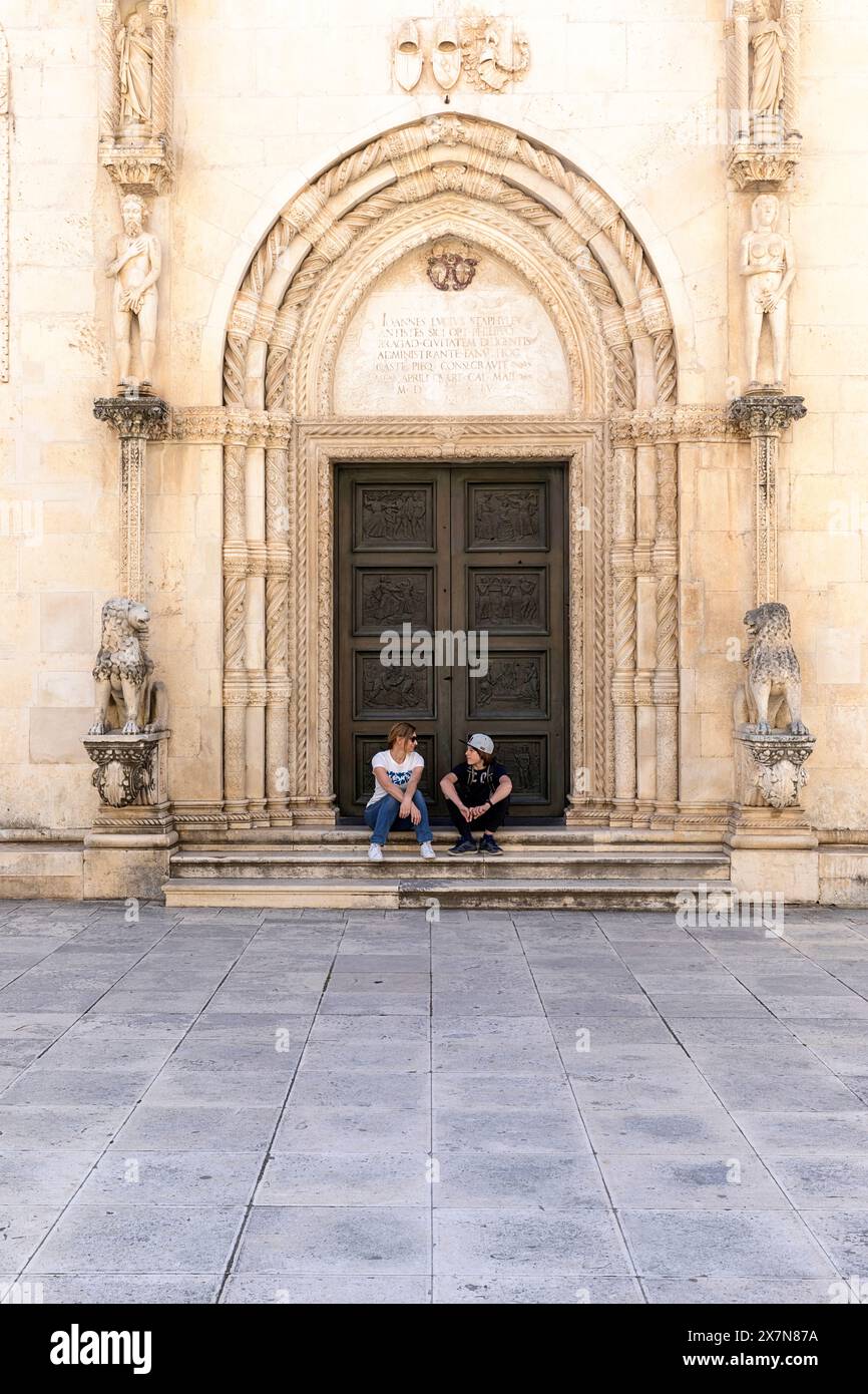 Touristes assis sur l'entrée latérale de la spectaculaire cathédrale de sain James dans la vieille partie historique de la ville de Sibenik, Dalmatie, Croatie Banque D'Images