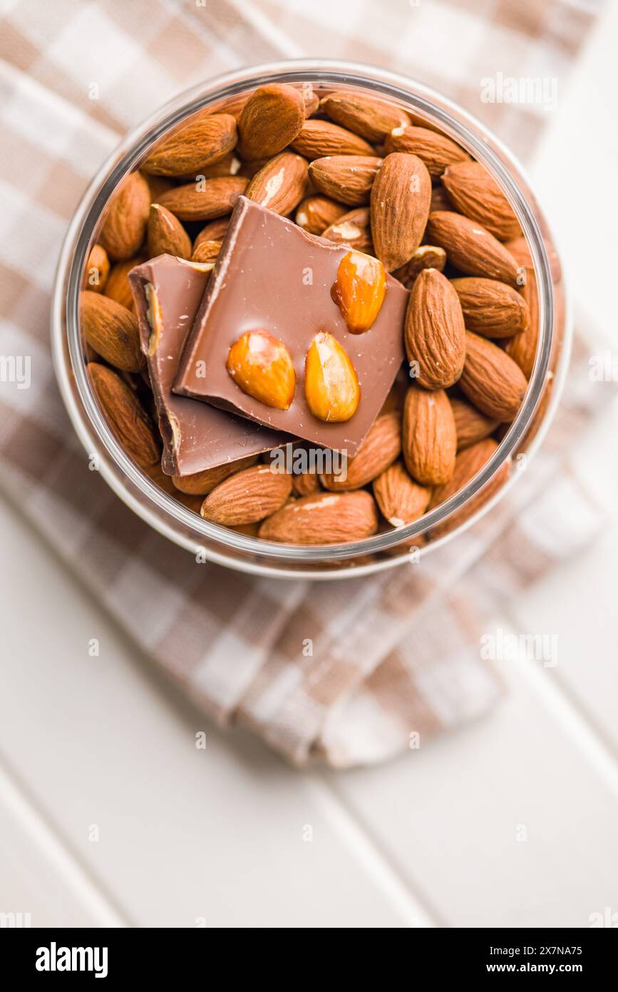 Barre de chocolat cassée avec des amandes dans un bol sur une table de cuisine. Banque D'Images