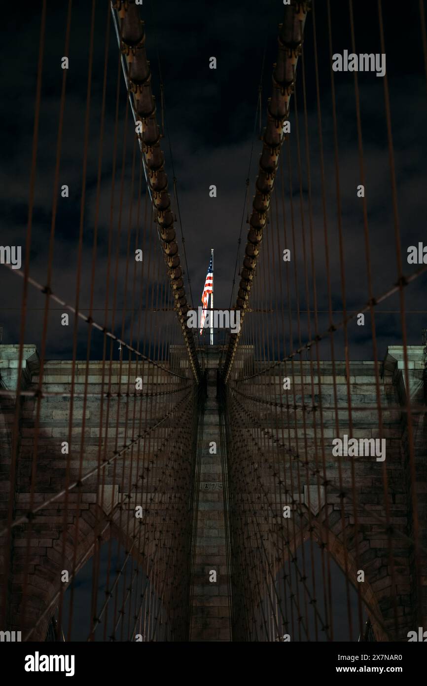 Pont de Brooklyn la nuit avec drapeau américain à New York Banque D'Images