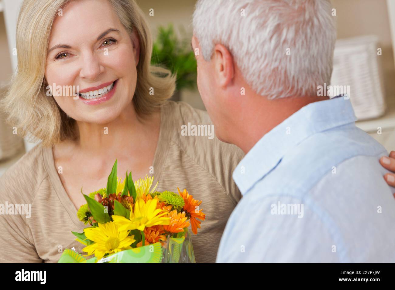 Femme âgée heureuse recevant des fleurs romantiques, homme senior et couple de femme à la maison souriant et en bonne santé Banque D'Images