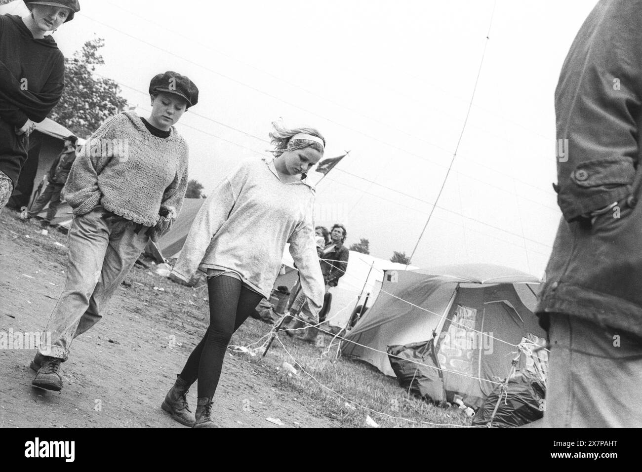 FESTIVAL GOERS, TENTE CITY, GLASTONBURY 90 : les gens errent dans un coin lointain de tente City dans des bottes boueuses croustillantes et des sauteurs après une tempête estivale au Glastonbury Festival, Pilton, Angleterre, 23 juin 1990. Photographie : ROB WATKINS. Banque D'Images FESTIVAL GOERS, TENTE CITY, GLASTONBURY 90 : les gens errent dans un coin lointain de tente City dans des bottes boueuses croustillantes et des sauteurs après une tempête estivale au Glastonbury Festival, Pilton, Angleterre, 23 juin 1990. Photographie : ROB WATKINS. Banque D'Images