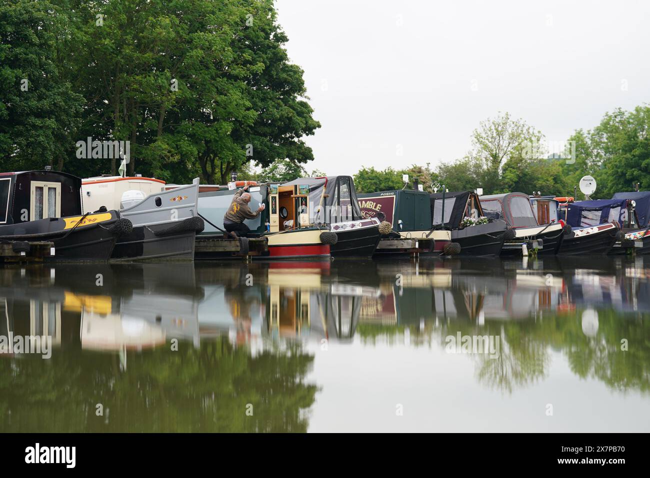 Un homme nettoie un bateau sur le canal, à Crick Marina à Crick, Northamptonshire, avant le Crick Boat Show pendant le week-end des vacances bancaires. Date de la photo : mardi 21 mai 2024. Banque D'Images