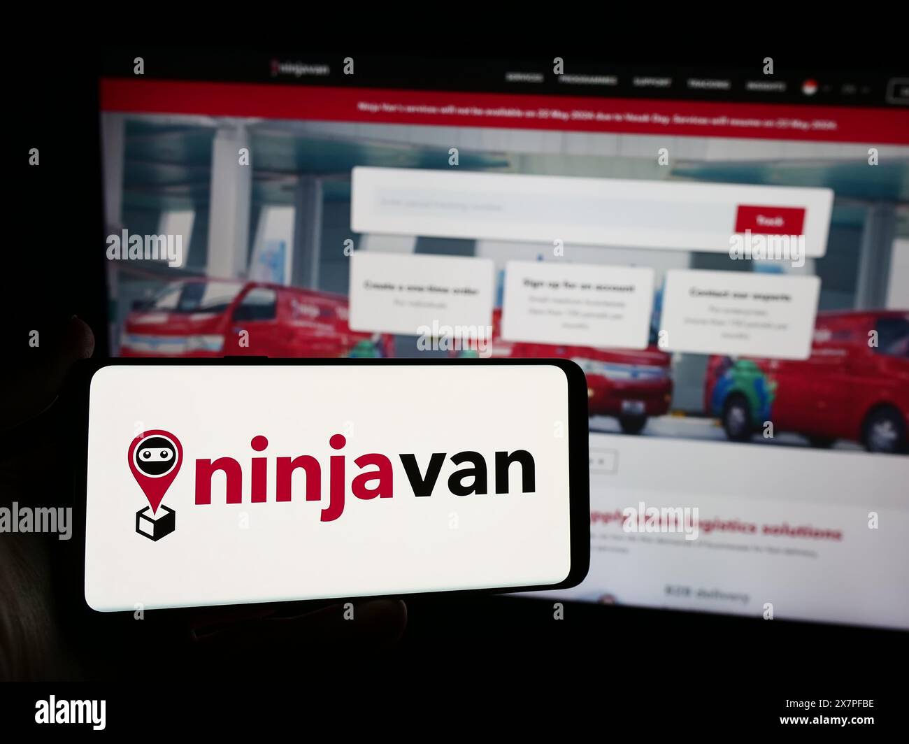Personne tenant un smartphone avec le logo de la société de livraison singapourienne Ninja Logistics Pte. Ltd en face du site Web. Concentrez-vous sur l'affichage du téléphone. Banque D'Images