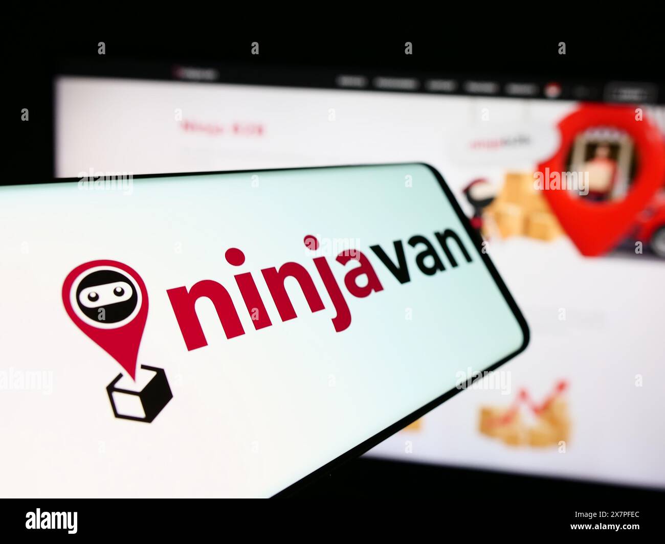 Smartphone avec le logo de la société de livraison singapourienne Ninja Logistics Pte. Ltd en face du site Web de l'entreprise. Focus à gauche de l'écran du téléphone. Banque D'Images