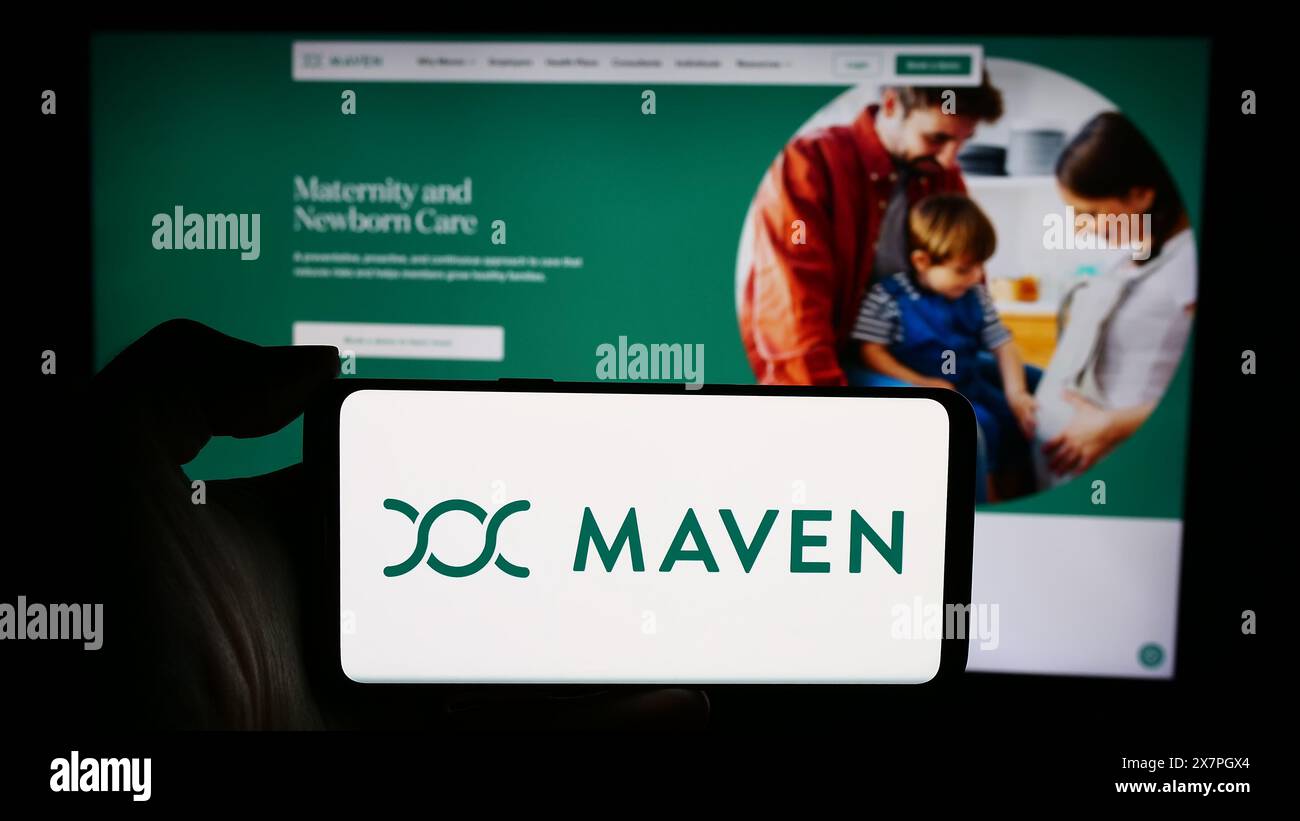 Personne tenant le téléphone portable avec le logo de la société de santé virtuelle américaine Maven Clinic Co. devant la page Web d'affaires. Concentrez-vous sur l'affichage du téléphone. Banque D'Images