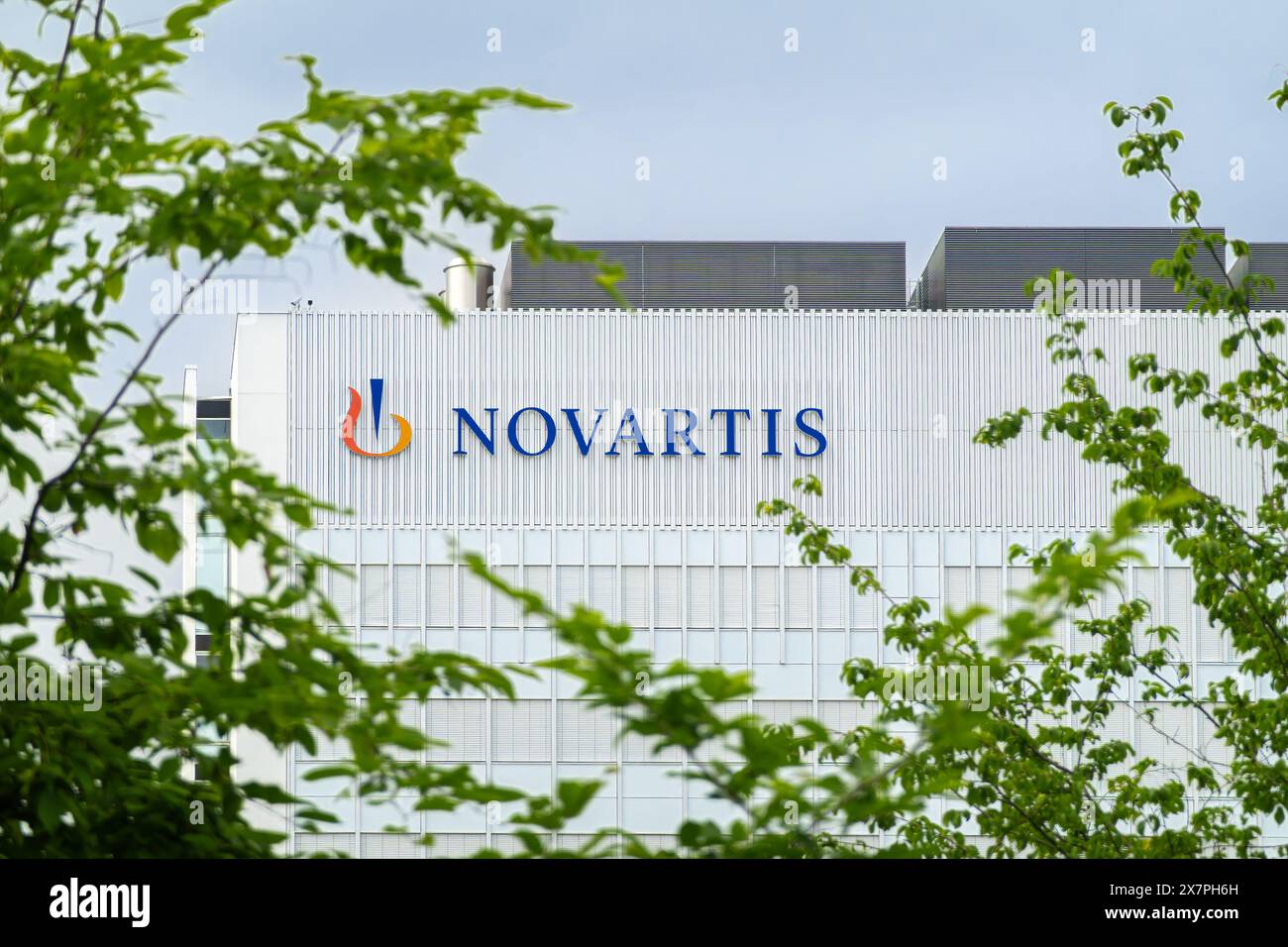 Bâle, Suisse - 18 mai 2024 : Siège de Novartis ou Novartis Campus, un bâtiment moderne entouré de verdure sous un ciel nuageux Banque D'Images