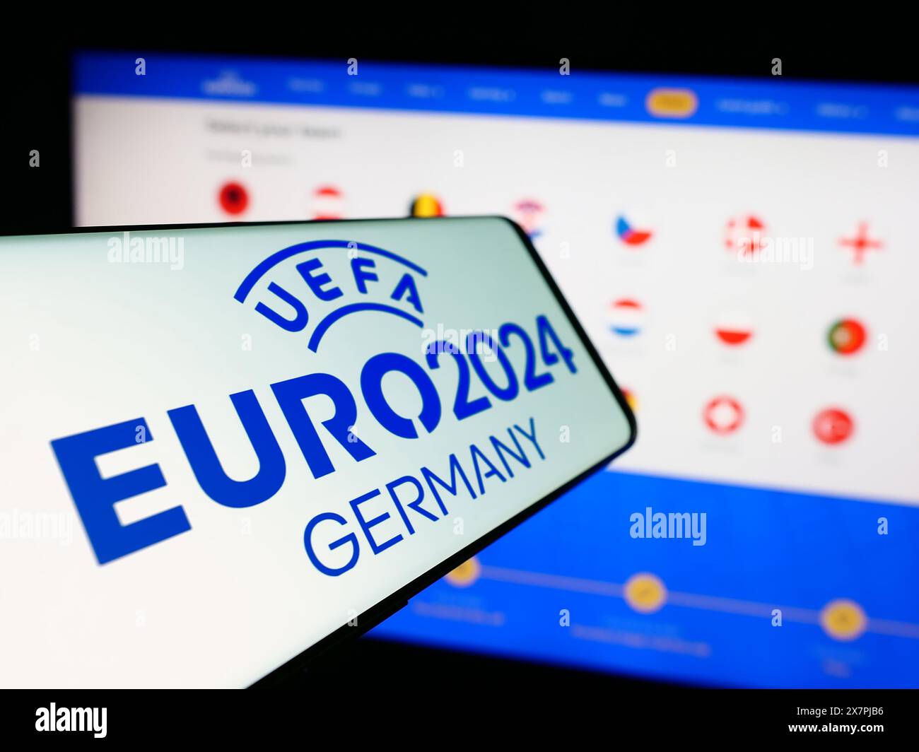 Téléphone portable avec logo du championnat d'Europe de football UEFA Euro 2024 en face du site. Mettez l'accent sur le centre-gauche de l'écran du téléphone. Banque D'Images