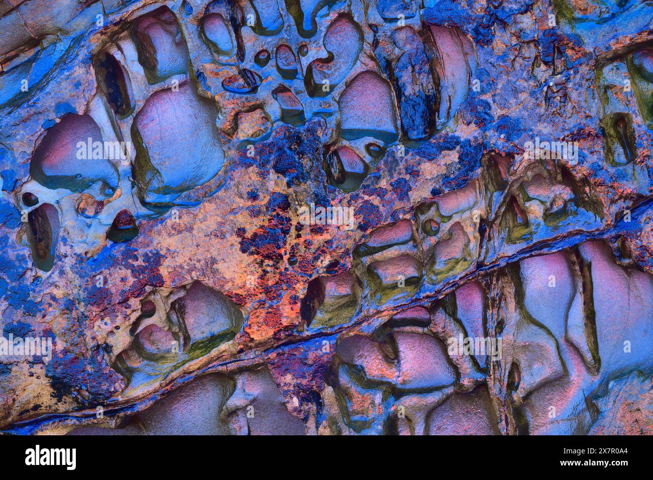 Cette image abstraite capture les schémas complexes de l'érosion sur les formations rocheuses, mis en évidence par une variété de couleurs vives. Banque D'Images