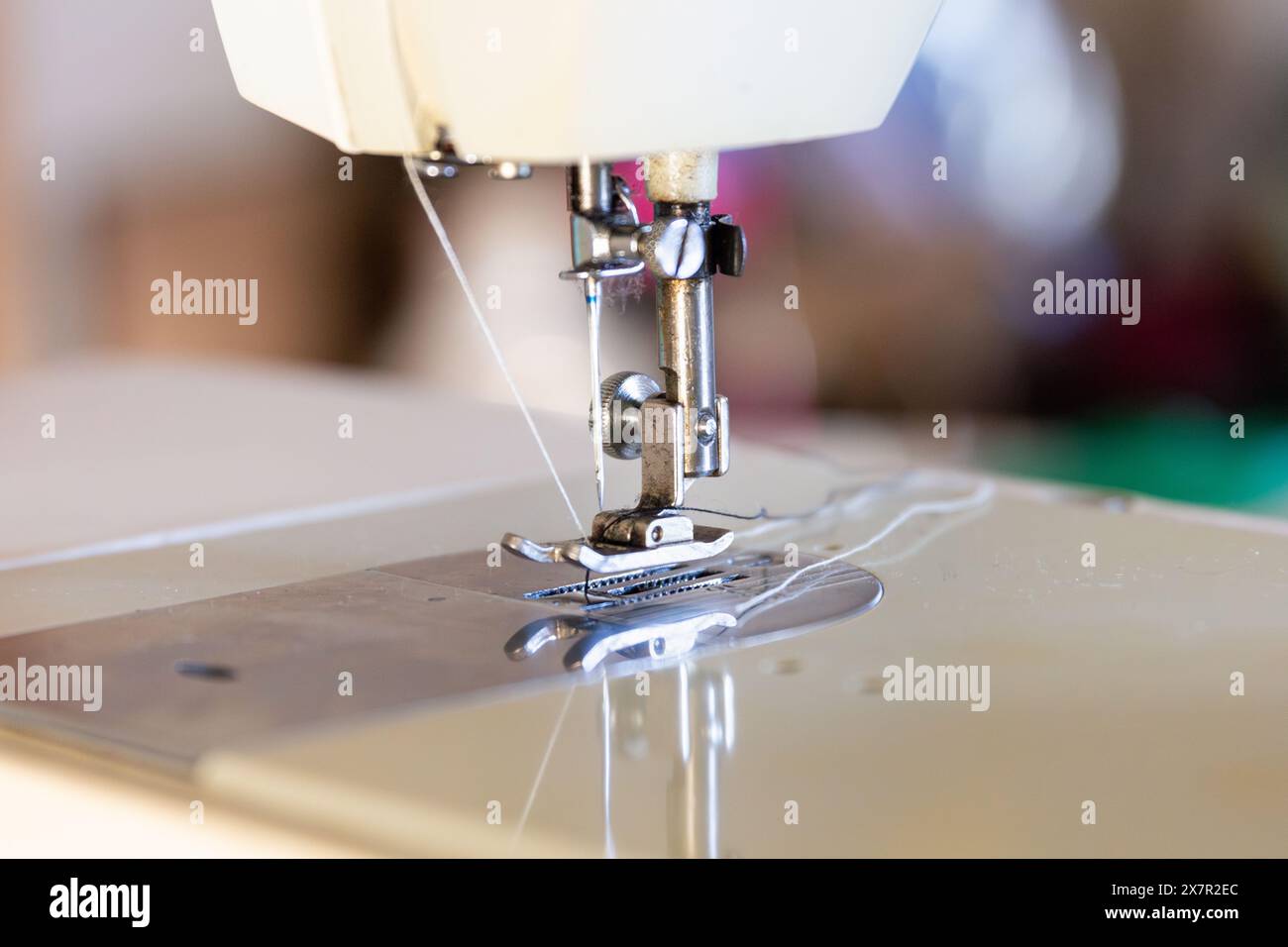 Une image en gros plan de l'aiguille et du pied-de-biche d'une machine à coudre, capturant les détails de l'équipement de couture dans un atelier de conception Banque D'Images