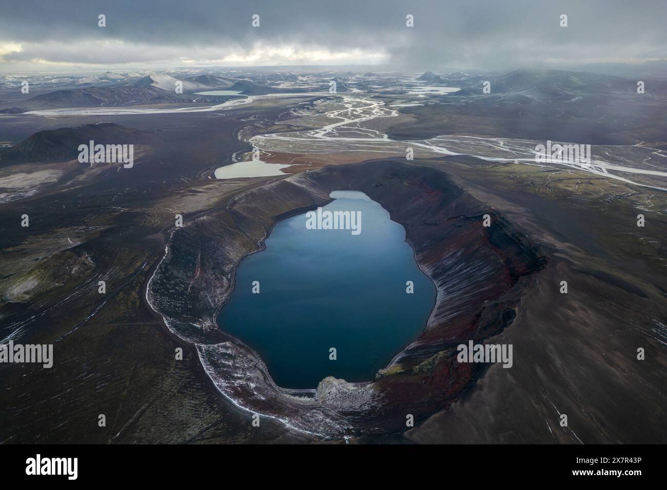 Une capture aérienne époustouflante met en valeur un lac tranquille niché dans le paysage spectaculaire et accidenté des terrains montagneux, sous un ciel sombre Banque D'Images