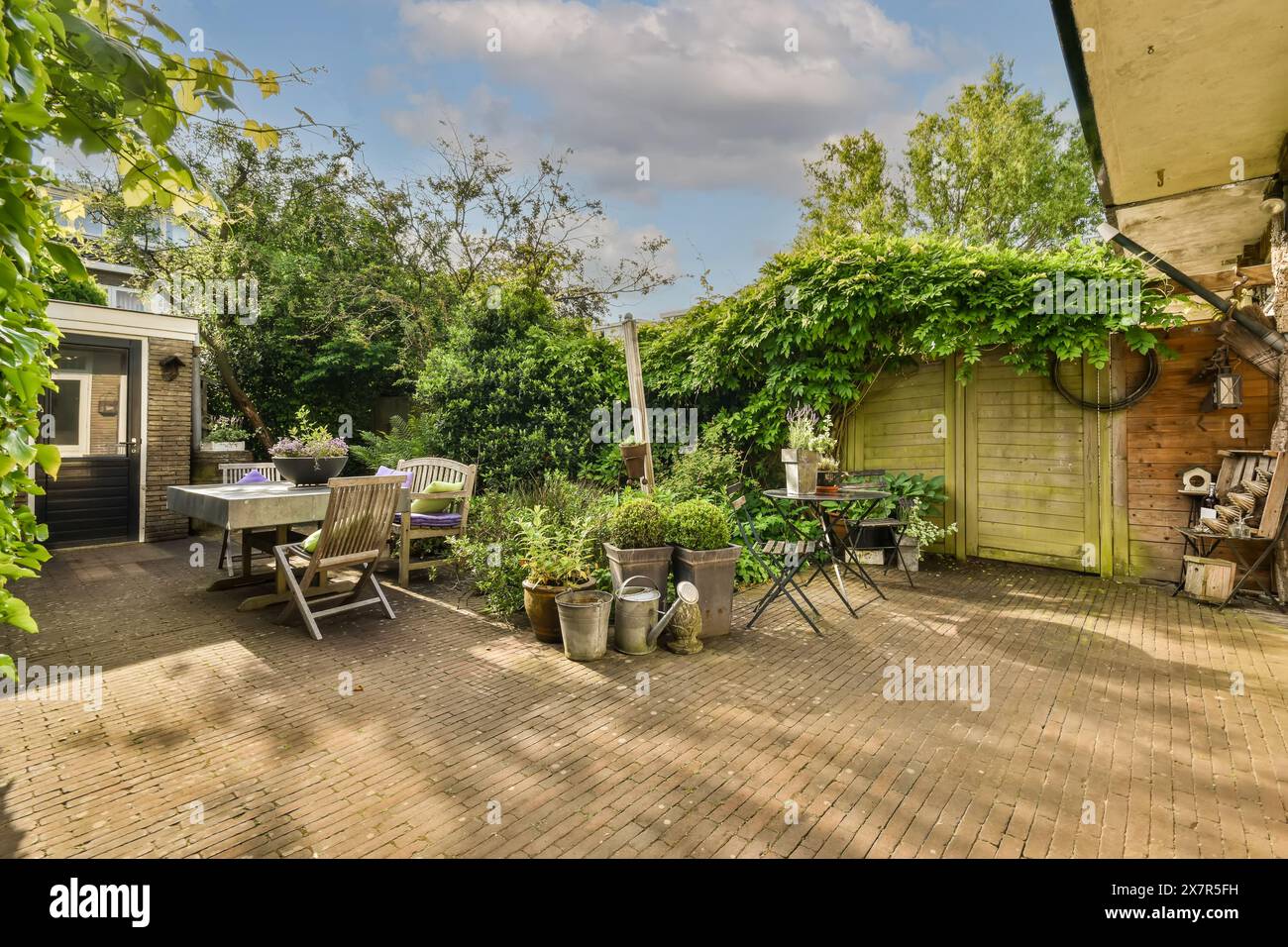 Un jardin pittoresque avec une salle à manger, une végétation luxuriante et des accents en bois au Meester Rendorplaan 8, parfait pour la détente en plein air ou le divertissement Banque D'Images