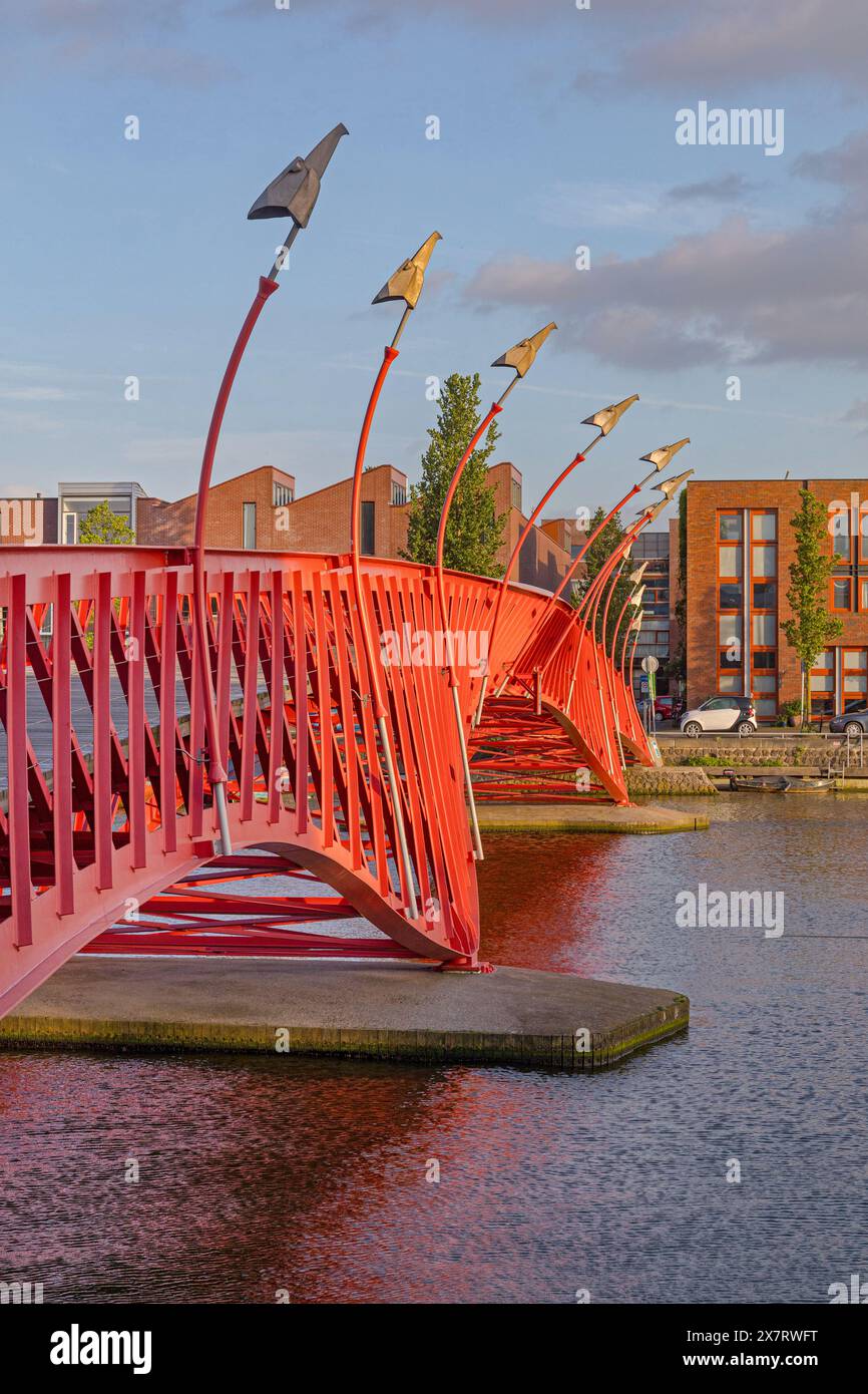 Amsterdam, pays-Bas - 17 mai 2018 : Pont piétonnier rouge Pythonbrug sur le canal d'eau dans l'après-midi de printemps est de la ville. Banque D'Images