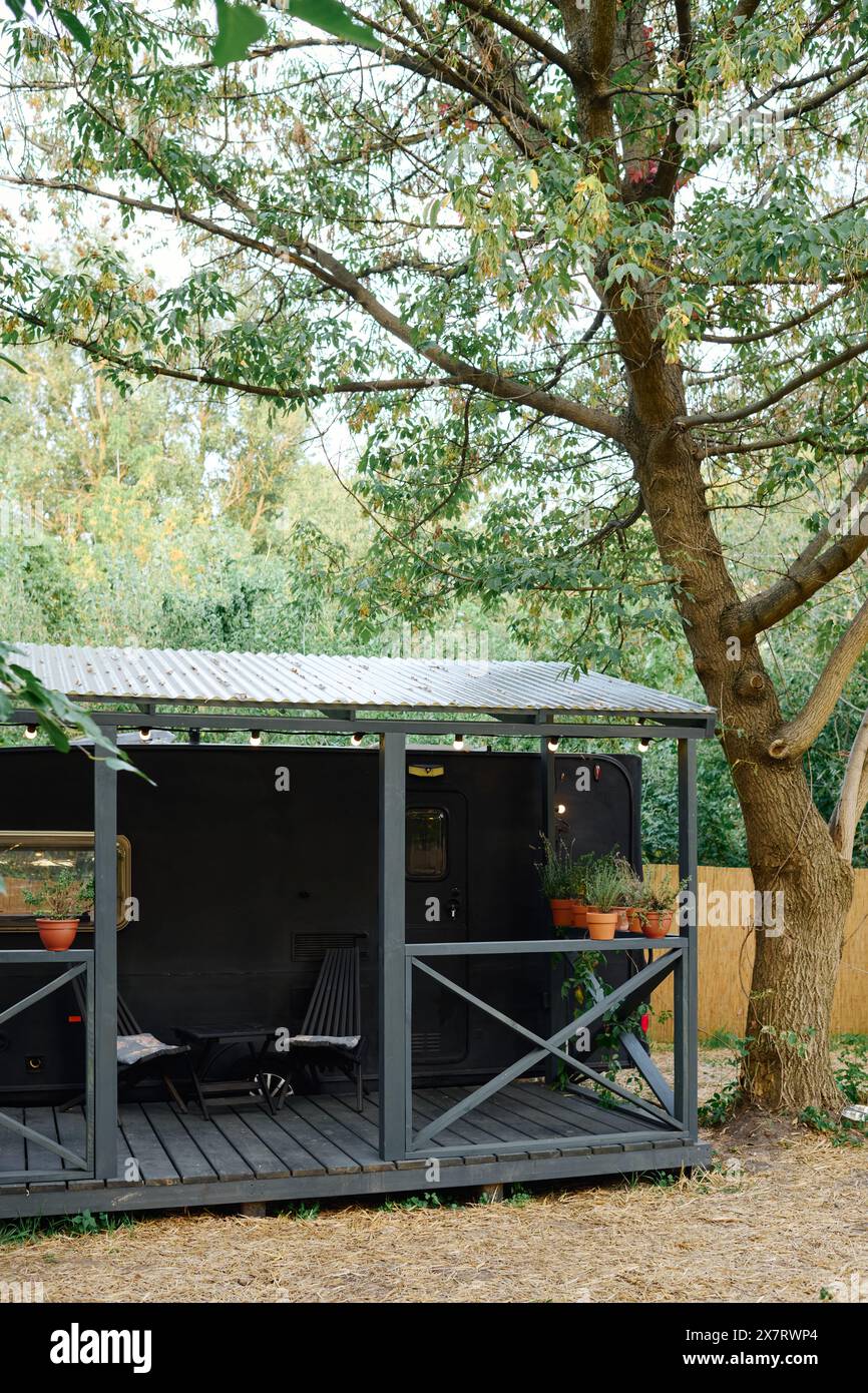 Un charmant petit hangar se trouve à côté d'un arbre majestueux, créant une scène pittoresque et sereine dans la nature. Banque D'Images