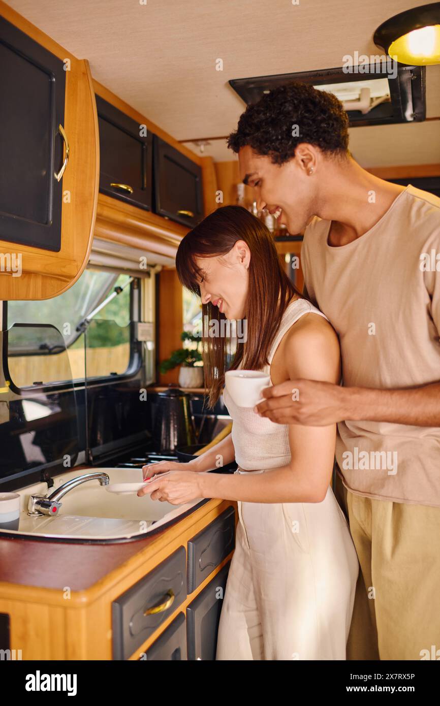 Un homme et une femme, de races différentes, debout ensemble dans une cuisine à côté d'un évier. Banque D'Images