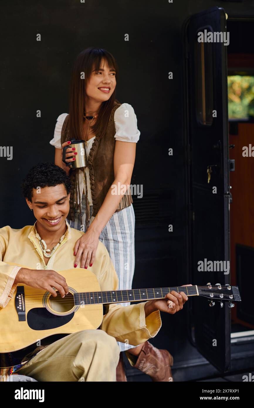 Un homme tenant une guitare à côté d'une femme, créant de la musique ensemble dans les environs sereins de montagne. Banque D'Images