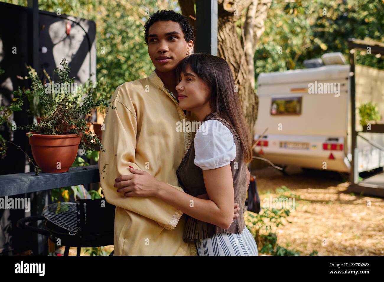 Un homme et une femme de différentes races debout côte à côte, embrassant, dans un cadre naturel serein lors d'une escapade romantique. Banque D'Images