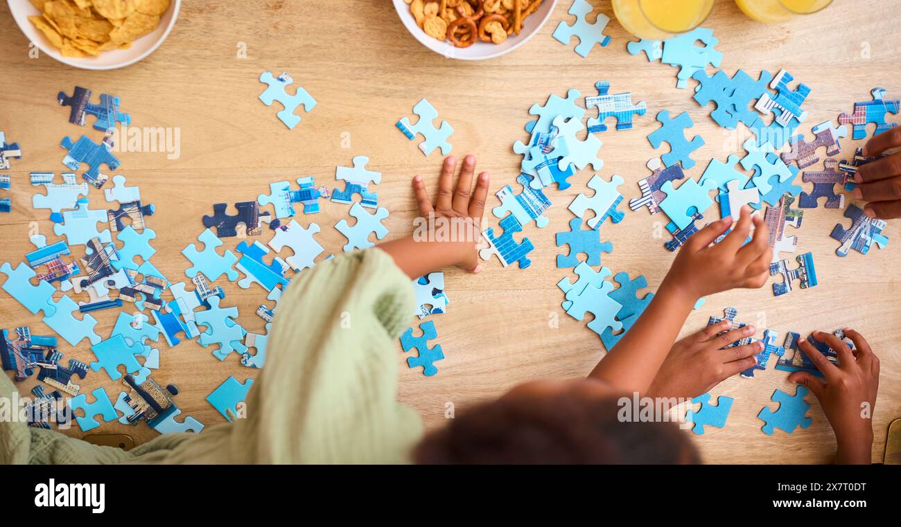 Gros plan en hauteur d'enfants à l'intérieur à la maison faisant un puzzle ensemble Banque D'Images